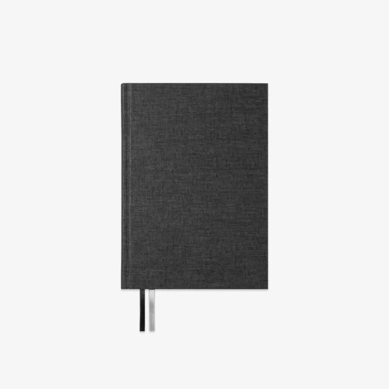A black linen-covered hardcover notebook with a black and silver ribbon bookmark, shown against a plain white background.