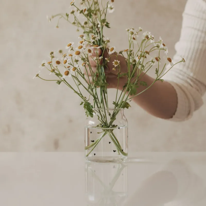 Glasvase mit schwarzen Herzen, mit locker arrangierten Blumen