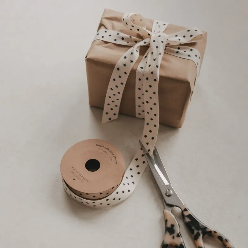 Beiges Geschenkband mit schwarzen Sternen, Geschenk, Rolle und Schere